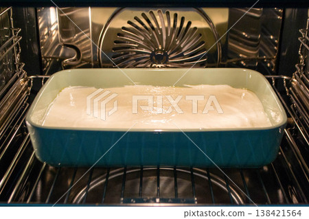 Cottage cheese casserole with raspberries and hazelnuts in a glass form is baked in the oven. Closeup. High quality photo 138421564