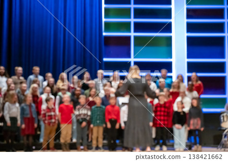 Defocused choir performs on stage during a holiday concert at a community center with many family members in the audience Defocused choir performs on stage during a holiday concert at a community center with many family members in the audience 138421662