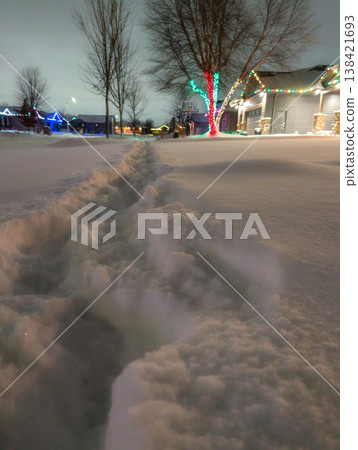 Snow path leads through winter scene with holiday lights at night in a quiet neighborhood in December Snow path leads through winter scene with holiday lights at night in a quiet neighborhood in December 138421693