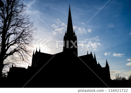 Silhouette of Historic Salisbury Cathedral stands tall against a clear sky in a small town in England during late afternoon light 138421722
