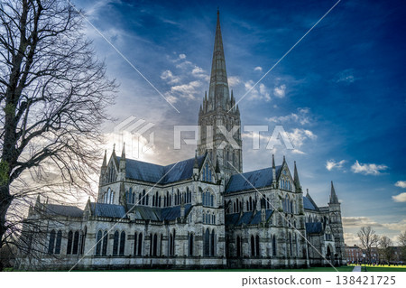 Historic Salisbury Cathedral stands tall against a clear sky in a small town in England during late afternoon light 138421725