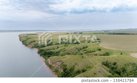 Beautiful riverside landscape with rolling hills and greenery near a calm water body in the afternoon light Beautiful riverside landscape with rolling hills and greenery near a calm water body in the afternoon light 138421784