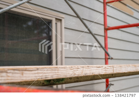 Construction crew prepares to work on residential building exterior using scaffolding on a cloudy afternoon 138421797