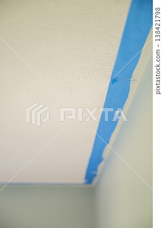 Preparation for painting a ceiling with blue tape in a home renovation project 138421798