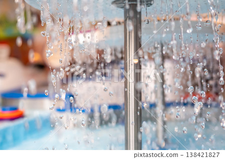 Water droplets cascade from a fountain in a vibrant outdoor setting during a sunny afternoon Water droplets cascade from a fountain in a vibrant outdoor setting during a sunny afternoon 138421827