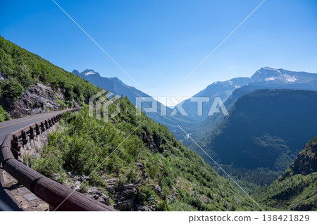 Scenic mountain drive showcases lush greenery and majestic peaks in the afternoon sunlight near Glacier National Park 138421829
