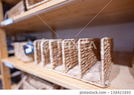 Woven storage baskets on wooden shelves in a home organization store for organizing items and creating a neat space 138421893