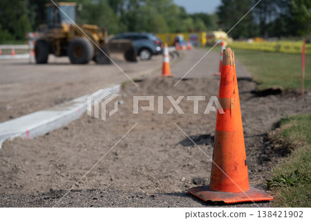 Construction work in progress on a road with equipment and traffic cones during daytime on a sunny day Construction work in progress on a road with equipment and traffic cones during daytime on a sunny day 138421902