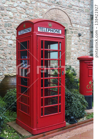 Red British Telephone Booth Standing Outdoors Near Stone Wall Red British Telephone Booth Standing Outdoors Near Stone Wall 138421927