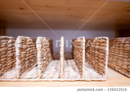Woven storage baskets arranged on a wooden shelf in a home storage area during daylight hours Woven storage baskets arranged on a wooden shelf in a home storage area during daylight hours 138422016