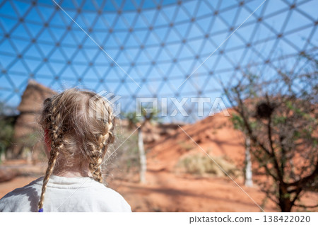 Child looks at large dome structure in desert area during daylight hours Child looks at large dome structure in desert area during daylight hours 138422020