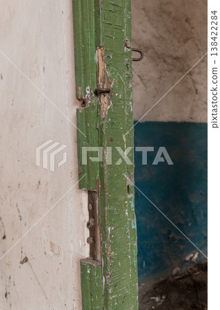 Weathered Green Wooden Door Frame With Peeling Paint And Rusty Iron Hinges In Abandoned Building Interior 138422284