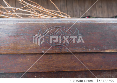 Intricate Fish Symbol Carved into Weathered Wooden Beam Displaying Rich Brown Tones and Textured Grain Against Rustic Background Intricate Fish Symbol Carved into Weathered Wooden Beam Displaying Rich Brown Tones and Textured Grain Against Rustic Background 138422299