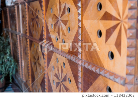 Intricate Wooden Panel Art With Geometric Star Patterns And Circular Cutouts In Warm Earthy Tones Displayed Outdoors Near Greenery Intricate Wooden Panel Art With Geometric Star Patterns And Circular Cutouts In Warm Earthy Tones Displayed Outdoors Near Greenery 138422302