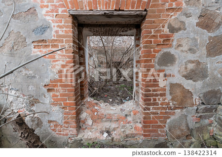 Dilapidated Brick Window Frame in Abandoned Building Wall with Peeling Plaster and Overgrown Vegetation Behind Dilapidated Brick Window Frame in Abandoned Building Wall with Peeling Plaster and Overgrown Vegetation Behind 138422314