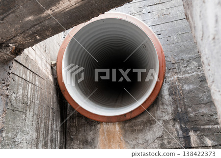Close-Up View Of A Large Industrial Corrugated Pipe With White Interior And Orange Rim Set Against Weathered Concrete Walls In An Underground Utility Tunnel Environment Close-Up View Of A Large Industrial Corrugated Pipe With White Interior And Orange Rim Set Against Weathered Concrete Walls In An Underground Utility Tunnel Environment 138422373