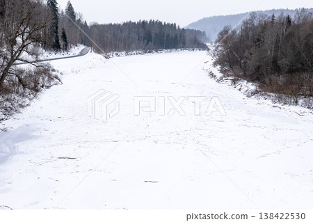 Frozen River Valley With Snow Covered Banks And Forest 138422530