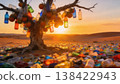 Surreal concept of plastic pollution in nature. A dead tree covered with hanging plastic bottles in a desert filled with trash at sunset. Environmental disaster and global waste problem 138422943