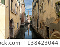 Narrow Venetian canal between weathered historic buildings 138423044