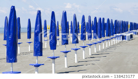 beach with closed sun umbrellas beach with closed sun umbrellas 138423177
