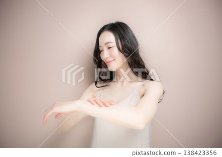 一張美麗的圖片,描繪了在手臂上塗抹乳霜或防曬霜的場景,背景是米粉色。 一張美麗的圖片,描繪了在手臂上塗抹乳霜或防曬霜的場景,背景是米粉色。 138423356