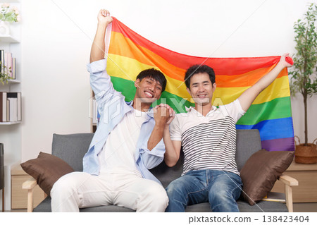 LGBTQ couple celebrating with a pride flag LGBTQ couple celebrating with a pride flag 138423404