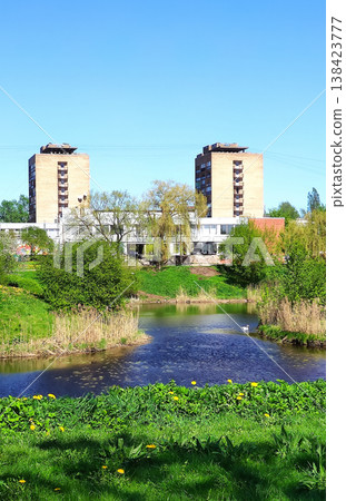 Urban park with a ponf and vibrant spring vegetation in bright daylight. Perfect for lifestyle photography, environmental awareness, and creative projects. 138423777