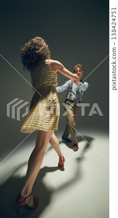 Couple dancing lindy hop holding hands spinning in studio dynamic retro movement. Couple dancing lindy hop holding hands spinning in studio dynamic retro movement. 138424751