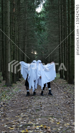 Two People in Ghost Costumes Walking on a Forest Path 138424765