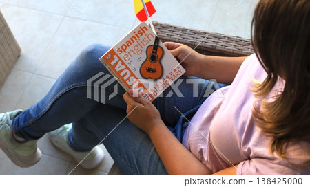 Woman reading Spanish-English dictionary featuring guitar illustration Woman reading Spanish-English dictionary featuring guitar illustration 138425000