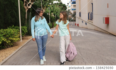 Mother and daughter walking to school holding hands on a sunny day 138425030