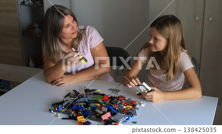 Smiling mother and daughter play with colorful building blocks, enhancing coordination and creativity 138425035
