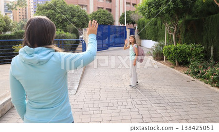 Mom and daughter share a loving goodbye wave before school. Backpacks ready Mom and daughter share a loving goodbye wave before school. Backpacks ready 138425051