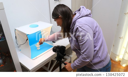 Woman sets up a white backdrop in a studio to take pictures of a small figure in good lighting for a project at home Woman sets up a white backdrop in a studio to take pictures of a small figure in good lighting for a project at home 138425072