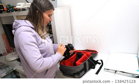 Woman organizing camera gear in a bag at home during the afternoon hours  138425128