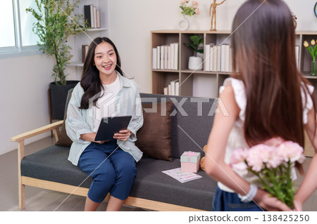 Daughter surprising her mother with flowers and a gift Daughter surprising her mother with flowers and a gift 138425250