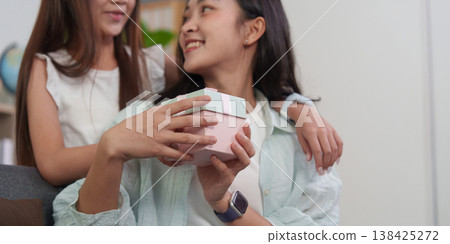 Mother receiving a gift from her daughter Mother receiving a gift from her daughter 138425272