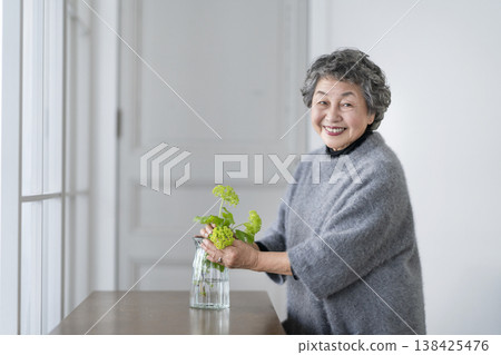 Senior woman decorating her room with flowers, portrait looking at camera and smiling Senior woman decorating her room with flowers, portrait looking at camera and smiling 138425476