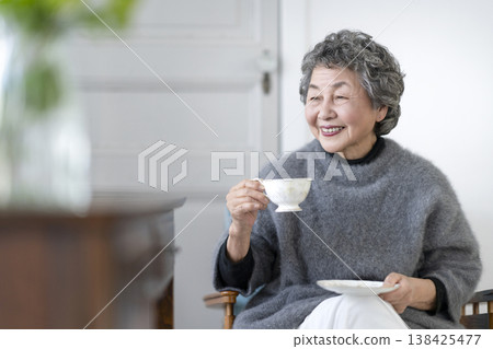 A smiling senior woman holding a teacup. A smiling senior woman holding a teacup. 138425477