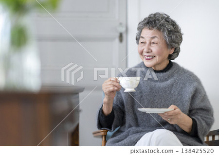 A smiling senior woman holding a teacup. 138425520