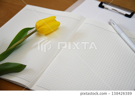 A spring desk photo featuring an open notebook, pen, and yellow tulips. A spring desk photo featuring an open notebook, pen, and yellow tulips. 138426389