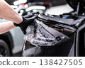 Applying PPF film on car headlights in professional detailing studio 138427505