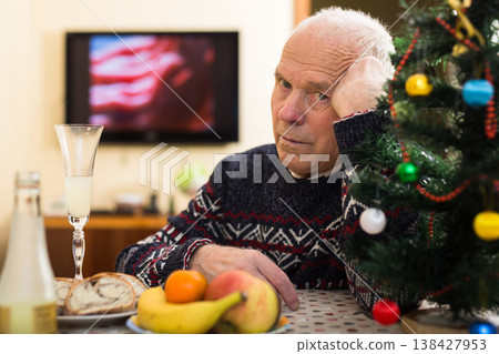 Lonely frustrated gray-haired senior man sitting at home table during Christmas celebration 138427953