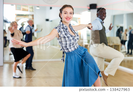 Cheerful female practicing lindy hop in pair with man Cheerful female practicing lindy hop in pair with man 138427963