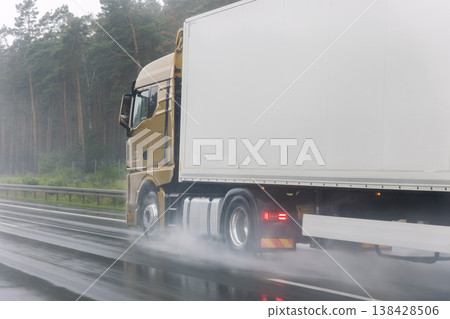 Close-up semi-trailer truck wheel driving fast Splashing Water on Highway, Risk of Aquaplaning on Wet Road. Detail view of hydroplane danger on rainy asphalt surface. Bad dangerous weather conditions 138428506