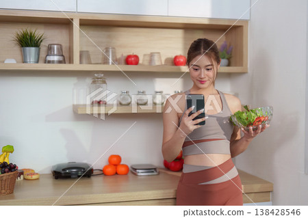 Young woman using a smartphone while holding a salad Young woman using a smartphone while holding a salad 138428546
