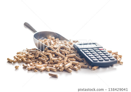 Calculator on Pile of Wood Pellets Representing Biofuel Cost, Renewable Energy Accounting and Fuel Efficiency Analysis 138429041