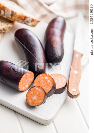 Smoked Blood Sausage Slices on White Cutting Board with Knife and Rustic Bread Smoked Blood Sausage Slices on White Cutting Board with Knife and Rustic Bread 138429050