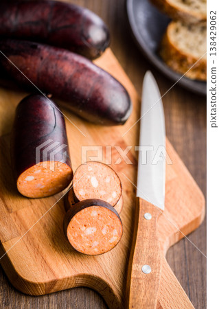 Smoked Sausage Slices On Wooden Cutting Board With Knife And Bread Rustic Kitchen Scene 138429062