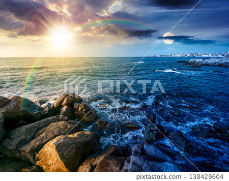 day meet night. sea coast with stones and boulders. view of beach with rock in seaweed. sun and moon on epic sky above horizon. autumn equinox harmony concept for astrology background day meet night. sea coast with stones and boulders. view of beach with rock in seaweed. sun and moon on epic sky above horizon. autumn equinox harmony concept for astrology background 138429604